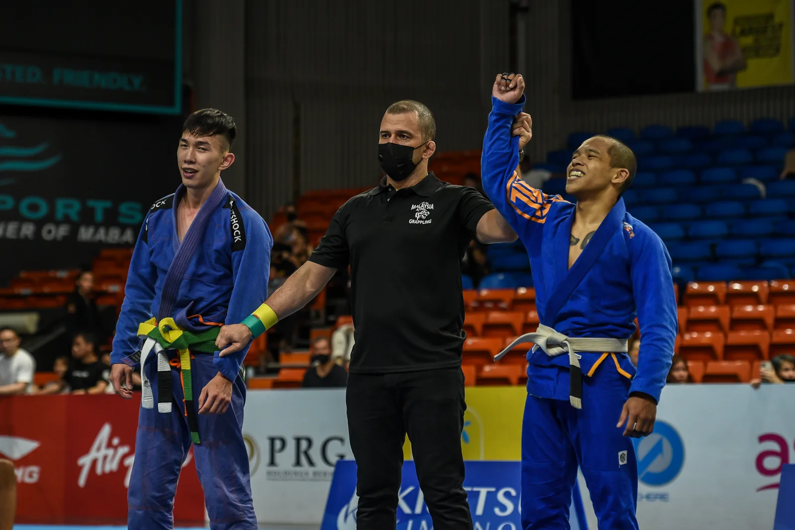 Coach Aiman's hand raised in victory at a national grappling championship