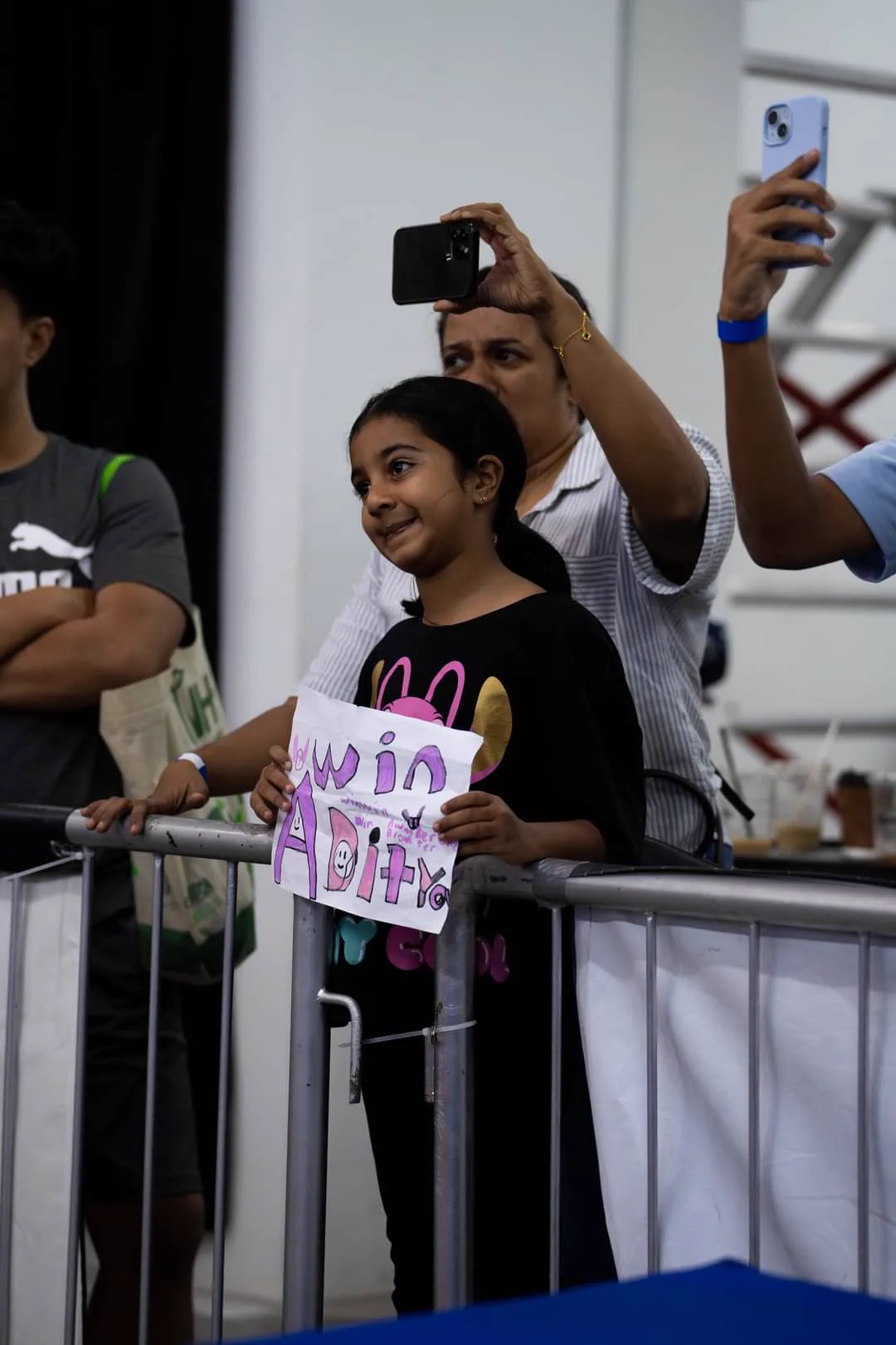 A young supporter holding a hand-drawn sign for an AZMA athlete at a community event